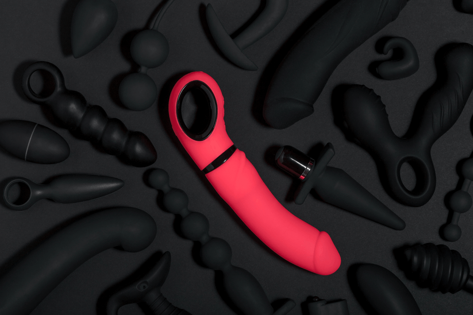 Pink vibrator with black sex toys on black background - eve's secrets sex shop