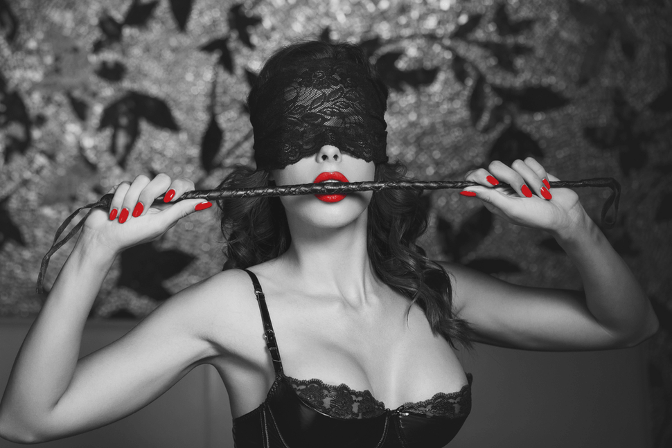 Sexy woman with red lips and nails biting the BDSM cane - eve's secrets sex shop