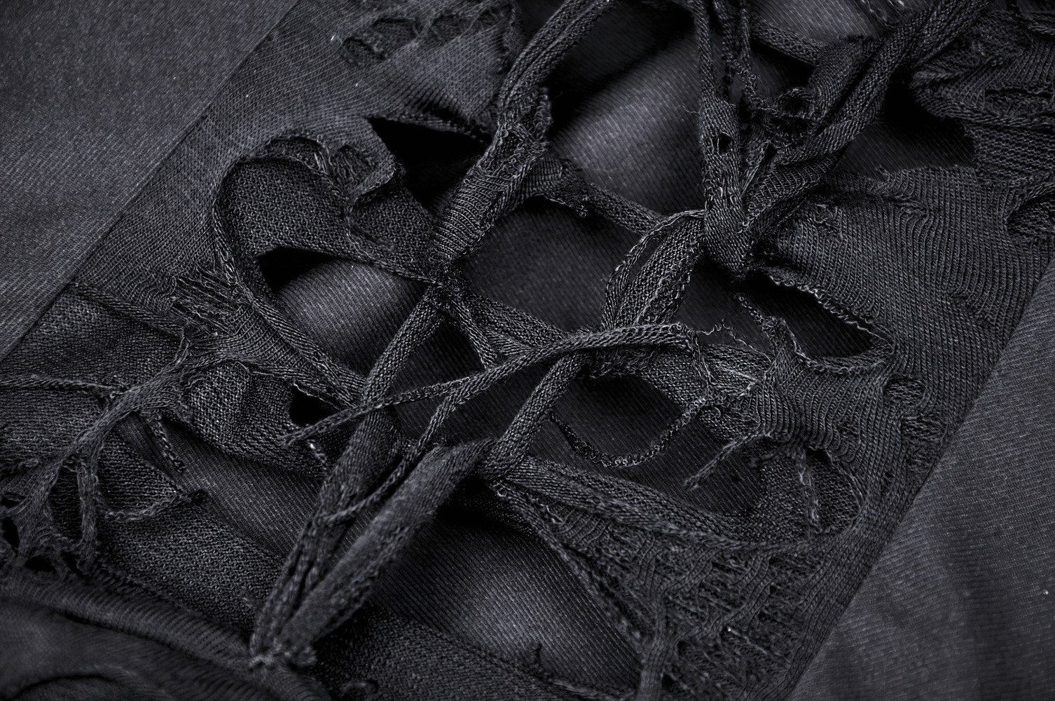 Close-up of intricate lace-up details on a black distressed dress, showcasing edgy gothic style and dramatic texture.
