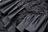 Close-up of elegant black fabric with ruffled texture and intricate lace detailing, capturing gothic style and dramatic flair.