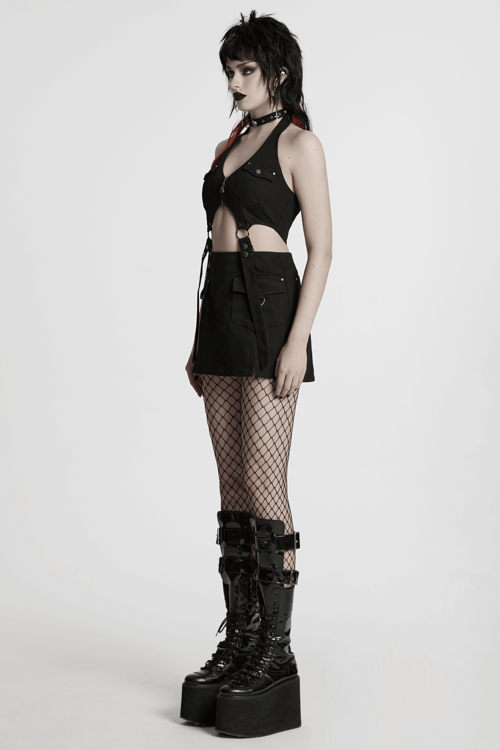 Punk halter neck dress with utility pockets, zippers, and straps, paired with fishnet stockings and platform boots.