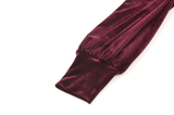 Close-up of puffy sleeve detail on a burgundy velvet dress, showcasing luxurious fabric and ruffled design.