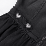 Close-up of a black dress showcasing heart-shaped metal accents and lace detailing.